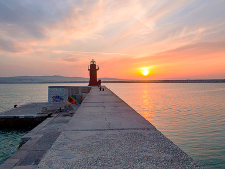 The lantern. Red lighthouse in Ancona's tourist and historic harbor with sky overcast with stunning...