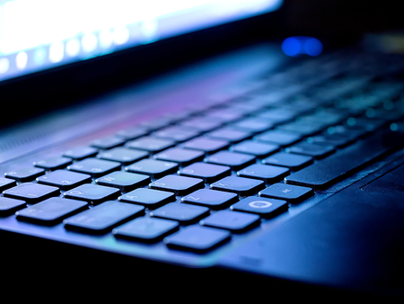 keyboard illuminated by the blue light of the computer screen with a white background in the background and soft-keyed buttonsの写真素材