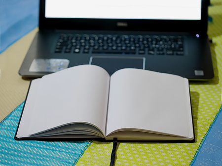 notebook with notepad with computer on background on colored tableの写真素材