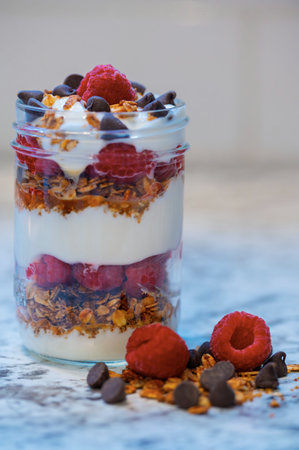 layered breakfast with yogurt, berries and crumble in a small glass jarの写真素材