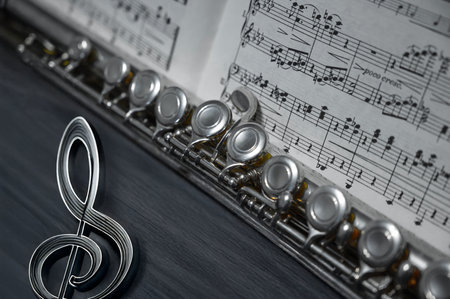 Silver flute and a music sheet on a wooden background close-upの写真素材
