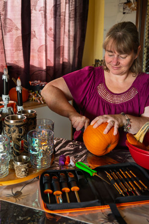 Woman carving a pumpkin for halloween in her home kitchen.の写真素材