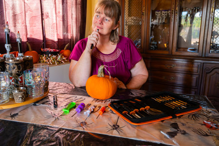 Woman thinking about how to carve a pumpkin for Halloween in her kitchenの写真素材