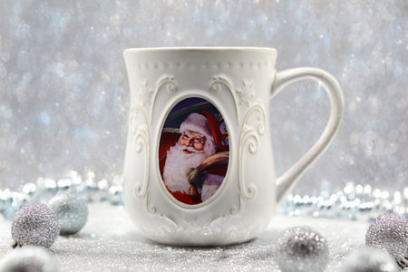 White mug with a picture of Santa Claus on the background of Christmas decorationsの写真素材