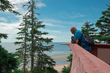A man with a camera stands on the bow of a boat looking the waterの写真素材