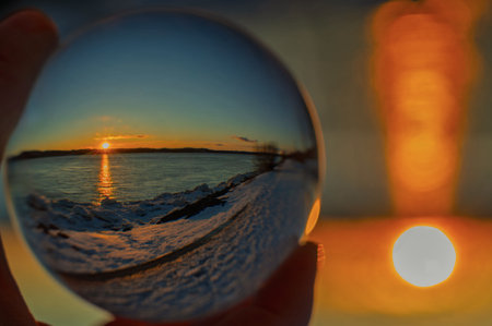 Reflection of the sunrise in a glass ball in winterの写真素材