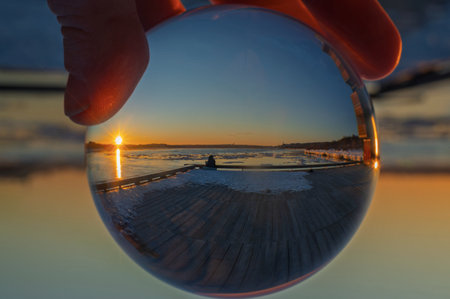 Reflection of the sunrise in a crystal ball on the frozen lakeの写真素材