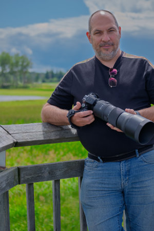 Portrait of a photographer with a camera on a background of green fieldの写真素材