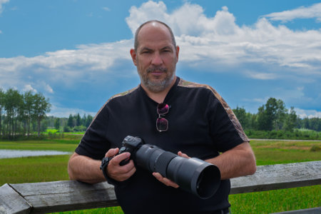 Portrait of a photographer with a camera on a background of green fieldの写真素材