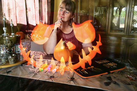 Woman imagining and visualizing how to carve a pumpkin for Halloween in her kitchenの写真素材