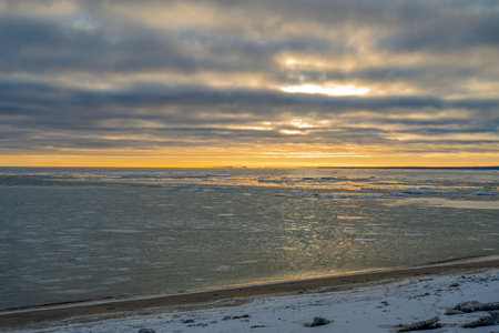 Beautiful winter sunrise over the frozen lake with colorful sky and ice formations at dawnの写真素材