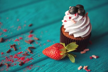 cupcakes with summer berries on blue wooden table.の写真素材