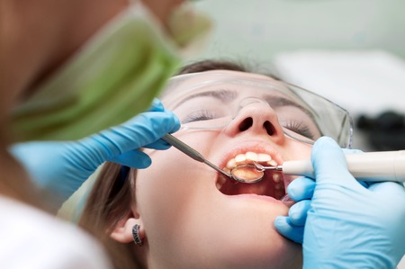 Close-up of female with open mouth during oral checkup at the dentist.Dentistの写真素材