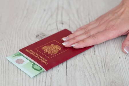 female hand holding a passport with Euro banknotes. Vacation in Europe.の写真素材