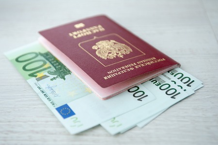 Russian passport lies on a pile of euro banknotes.