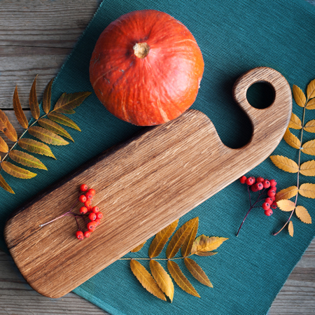 pumpkins yellow leaves and cut board on a wooden background in kitchenの写真素材