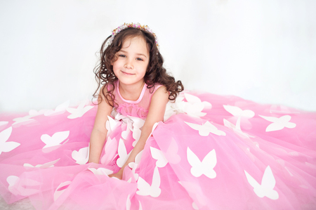 Portrait of smiling little girl in princess pink dress with butterflies.の写真素材