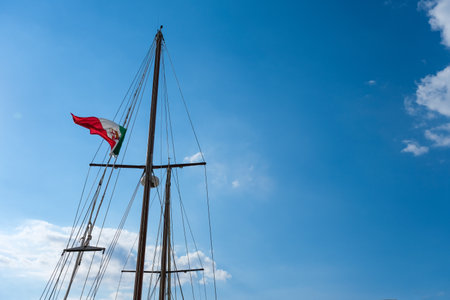 mast of a sailboat with the italian flag blowing in the wind