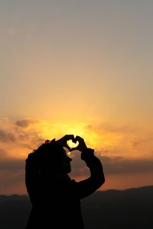 Silhouette of a heart shape with handsの写真素材
