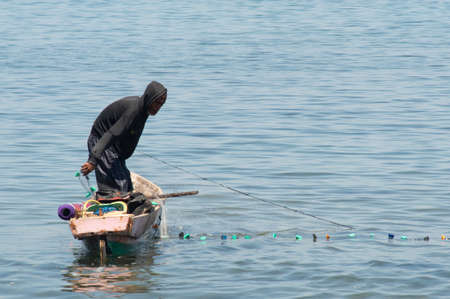 Maumere, Flores island, Indonesia - January 13 2015: Portrait of a fisherman netting on a little boat.のeditorial素材