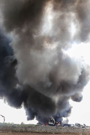 Big column of smoke coming from a burning cars