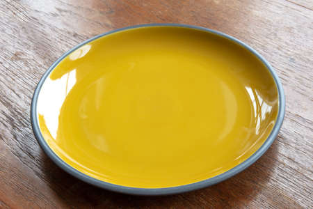 Empty yellow plate isolated on a wooden tableの写真素材
