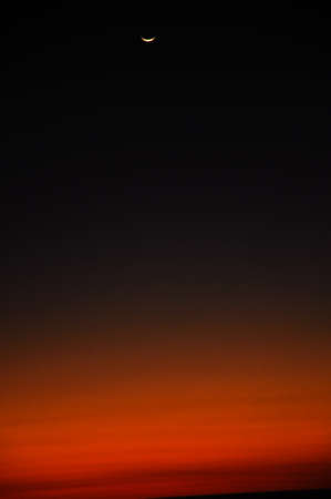 Red and dark dramatic sunset sky over the horizon water with moonの写真素材