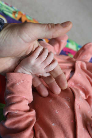 Little baby hand holding father`s finger representing father-and-child love, intimacy, and...