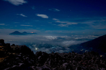 Night view of the Mount Merbabu with the light of the city on the valleyの写真素材