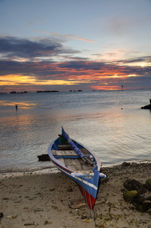 Traditional sailing and rowing fisherman boat. Dramatic gold sunset sky backgroundの写真素材