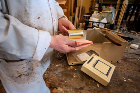 Craftsmanship, craftsman. Gilder at work with gold leaf for gilding restoration.