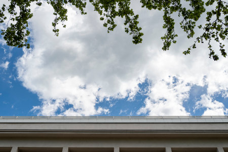 Blue sky and white clouds over the roof of a modern house.