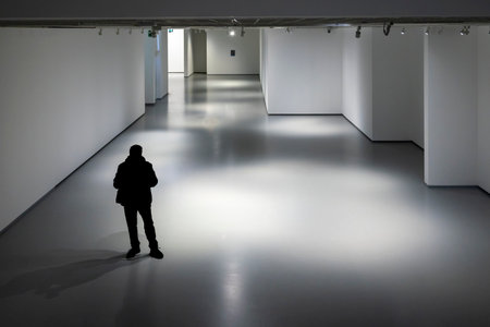 Silhouette of a man walking in an empty gallery with lights