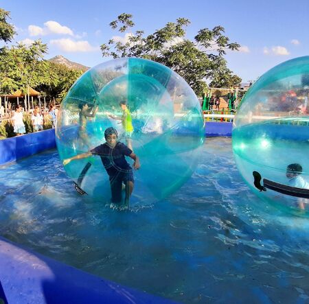 evocative image of a child having fun inside the inflatable ball floating on the water in the pool