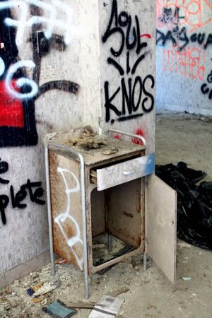 2019.06.16 - Limbiate, Milan, Italy, photographic reportage madhouse in Mombello, abandoned psychiatric hospital bedside table abandoned and overturned against a wall colored with spray paintの写真素材
