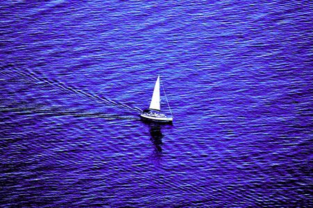 evocative image of a sailing boat sailing in a blue sea with sails unfurled