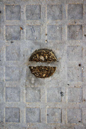 evocative texture image of plastic manhole cover with embossed square designs and a screw