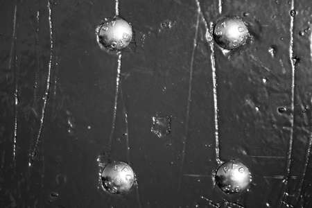 evocative black and white image of scratched and ruined wooden surface with four metal bolts