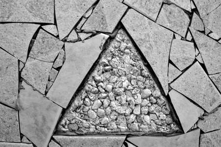 evocative black and white image of irregular brick texture with the design of a triangle in the centerの写真素材