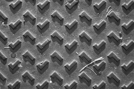 evocative image of black and white texture of metal plate with embossed square patterns