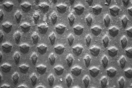 evocative image of black and white texture of metal plate with embossed square patterns