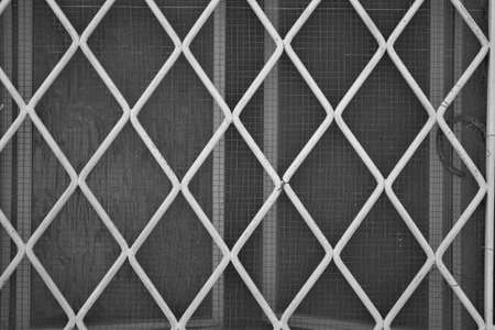 evocative black and white image of rhombus shaped white iron grate textureの写真素材