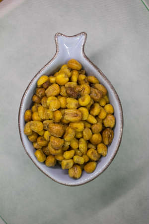evocative image of toasted corn for aperitif in a blue bowl in the shape of a fish with green...