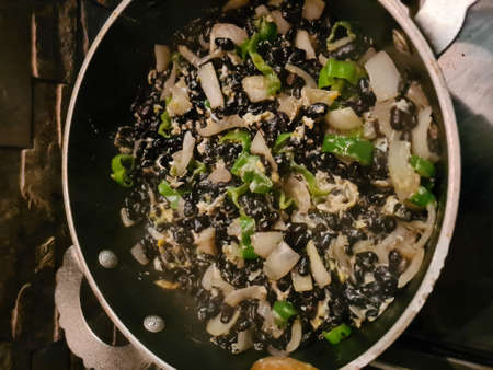 evocative image of cooking in a pan of a vegetarian dish based on black beans, onions and peppersの写真素材