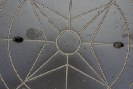 evocative textured image of a manhole in the shape of a compass roseの写真素材