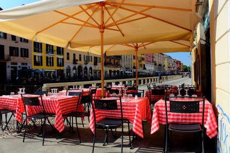 evocative image of tables set on a sunny day on the canals in Milanの写真素材