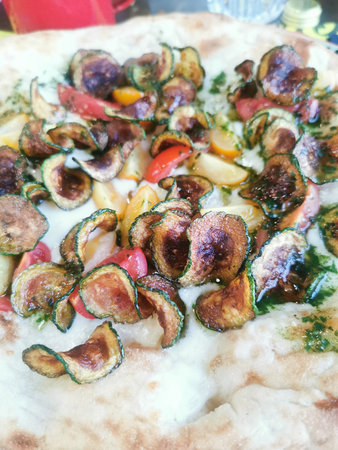 Crispy zucchini chips and colorful cherry tomatoes on a creamy, wood-fired pizza crust.の写真素材