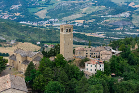 A sweeping view of San Leo perched on its rocky cliff, framed by the soft, undulating hills of...