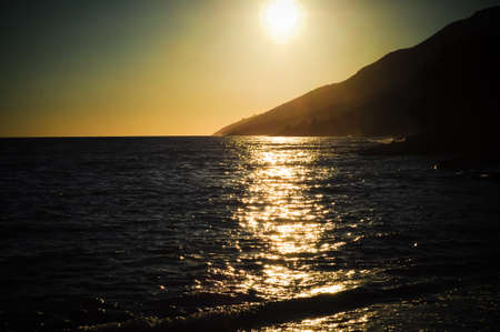 Croatia - sunset over the sea and the sun reflecting on the waves. In the background mountainsの写真素材