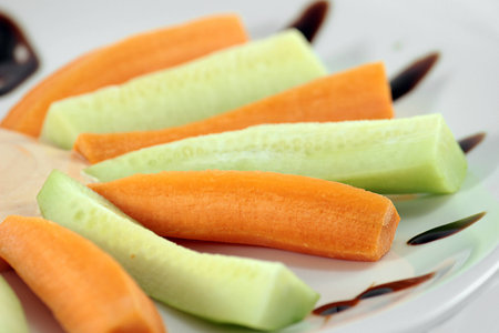 Sliced carrots and cucumbers on a plateの写真素材
